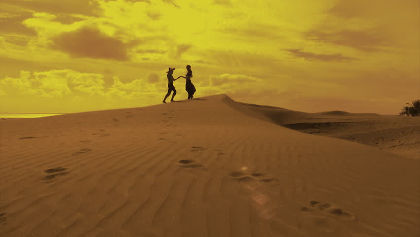 Young couple holding hands and dancing together in a desert landscape