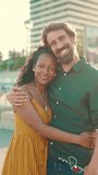 VERTICAL VIDEO, Close-up portrait of happy couple in the port, backlighting Closeup, young woman and man hugging and smiling looking at on camera, background and yachts. Camera zooming