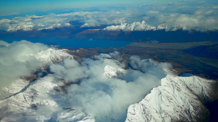 South Island Queenstown New Zealand snowy mountain peaks aerial drone flight high altitude winter cloudy beautiful sunny morning afternoon Lake Wanaka Wakatipu landscape circle to the left movement