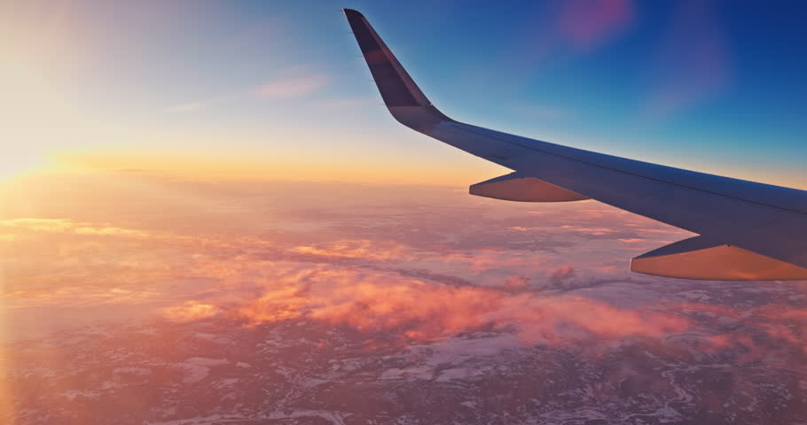Airplane fly over snowy mountain hills during scenic sunrise with color sky cloudscape, view from plane window of wing turbine and skyline 4k video
