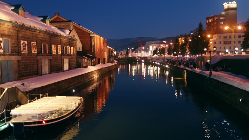 winter in Hokkaido, Japan, evening lights near Otaru Canal, city of Otaru in winter, tourism in Japan. Welcome to Otaru is written in Japanese on the wall of a historic building. 