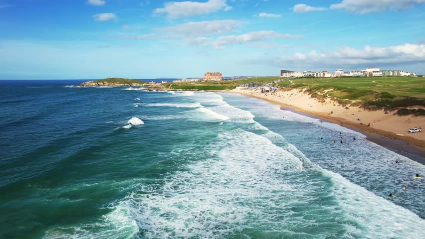 Fistral Beach Views with Surfing Waves on a Summers Day in Cornwall. Aerial Dolly Push In Drone Shot.