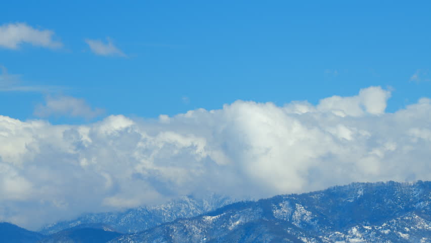Amazing Panorama Of Snow-Covered Hills. Mountains With Snow In Winter. Clouds Running Opposite Direction On Blue Sky. Timelapse.