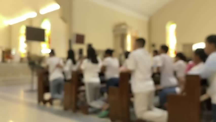 People praying in a Catholic church, blurry image out of focus.