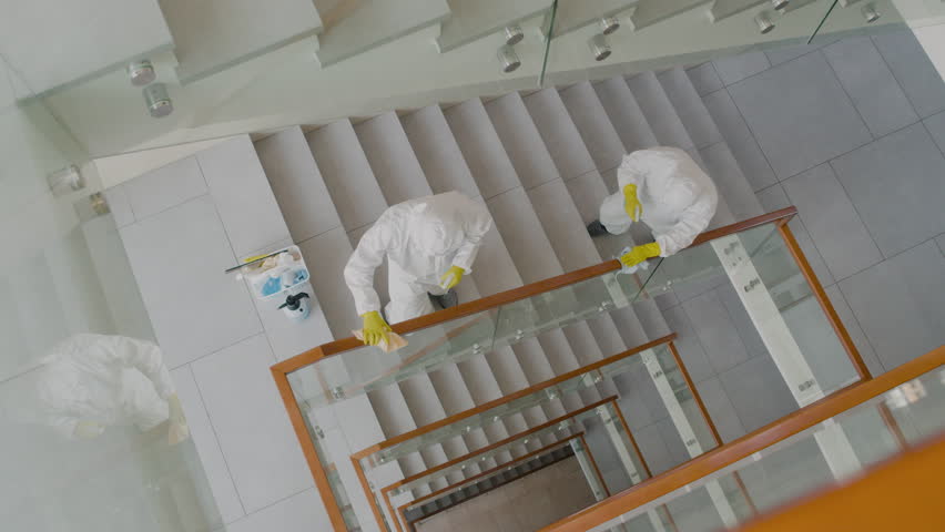 Top View Of Two Cleaning Men Wearing Personal Protective Equipment Cleaning Stair Railings Inside An Office Building Royalty-Free Stock Footage #3444121347