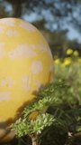 Three decorated Easter eggs are scattered on the grass in the forest among yellow flowers, Dolly slider extreme close-up. Dolly slider extreme close-up. Vertical video Social Media