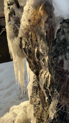 Spring touch in a narrow crevice with melting icicles and snow.