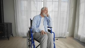 Old man in wheelchair looks at window. Thoughtful gray haired senior male at home enjoying pastime leisure. Living with physical legs trauma paralysis, sadness, loneliness of older people concept. - Powered by Shutterstock - Get 15% off with code: PIKWIZARD15