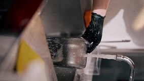 vertical video close-up of a woman washing dirty dishes in the kitchen after using professional equipment