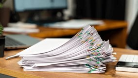 Bundle of documents, sheets with important information taken from large pile on table fastened with colored paper clips timelapse. Accounting workplace with laptop and calculator at home office