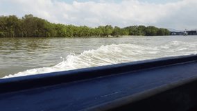 Traveling on a wooden long-tail boat, Thailand, Southeast Asia. Waves emanating from the side of the skiff.