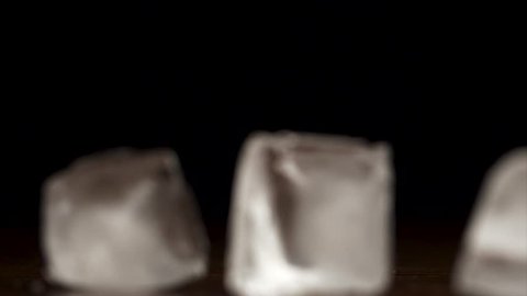 Ice cubes falling and bouncing on black background in slow motion. Ice drops on black background