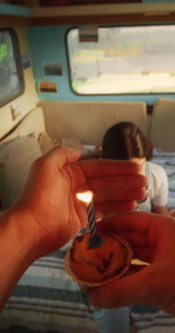 Vertical Screen: Caring Partner Bringing a Birthday Cupcake Muffin with a Candle to a Beautiful Young Girlfriend. Tourist Couple Living in a Caravan, Road Tripping Across the Country and Camping.