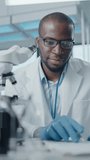 Medical Research Laboratory with Male Scientist Looking Under Microscope, Analysing Biotechnology Sample. Advanced Scientific Lab for Drugs, Vaccine Development, High-Tech Equipment. Vertical Video