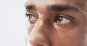 Close-up of a young biracial man's eyes on a white background. His gaze is intense, suggesting deep thought or emotion, slow motion.