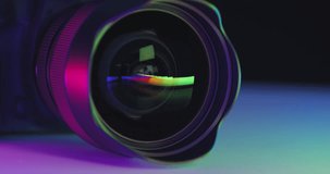 colorful play of colors is reflected in wide lens of photo camera lying on table, cinematic shot