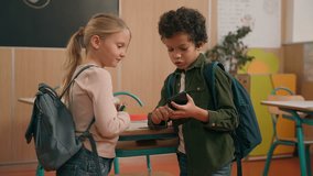 African and Caucasian little elementary school children multiracial diverse girl and boy kids pupils schoolchildren class study in classroom friendly talking using mobile phone holding smartphone talk - Powered by Shutterstock - Get 15% off with code: PIKWIZARD15