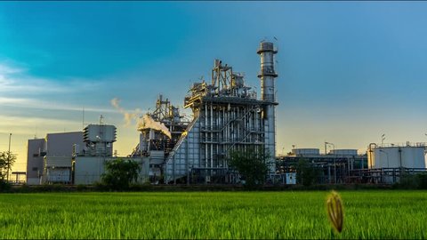 4K. Time Lapse Oil and Gas refinery industry plant.air pollution from smokestacks under cloudy sky with green Meadow.