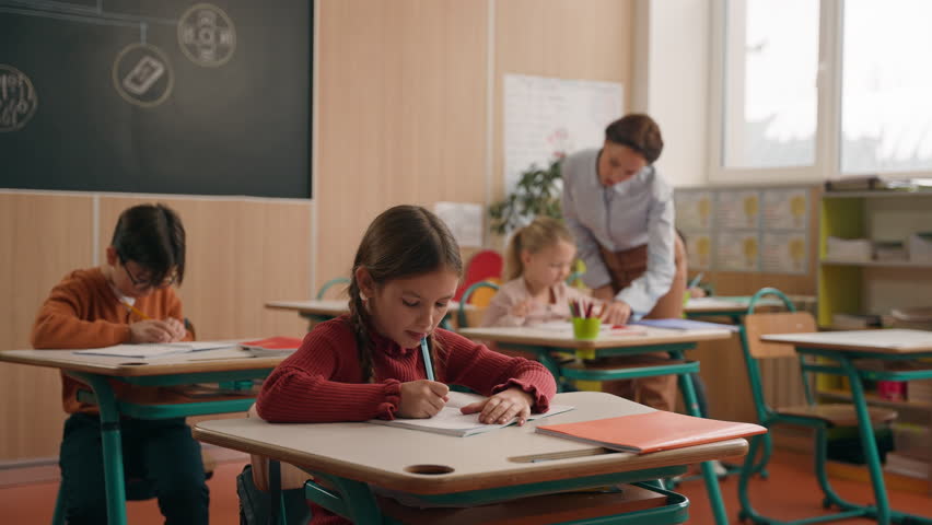 Caucasian woman teacher female tutor walking between classroom tables desk in elementary school teach children help with test task check exercise in notebooks class kids writing teach studying lesson Royalty-Free Stock Footage #3444347707