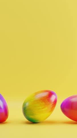 Three colorful eggs sitting on yellow surface with yellow background. Vertical looped animation. Royalty-Free Stock Footage #3444362507