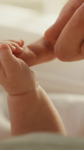 Vertical Format Video of a Close Up with Newborn Baby Hand Holding Mother's Finger while Lying in Child's Crib at Home. Concept of Childhood, New Llife, Parenthood.