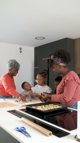 African family cutting cookie shapes in a cookie dough in the kitchen. Horizontal extended family.
