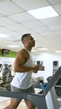 Strong Hispanic man running on treadmill at a gym.