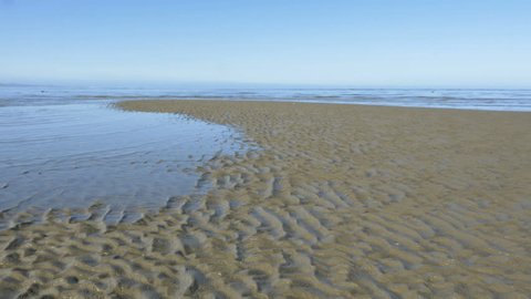 Time lapse of incoming tide, sea water level rising, taking over the beach, waves covering the golden sand, rib pattern stretching out, South Island coast, New Zealand