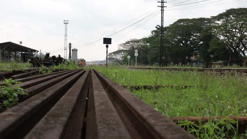 Low angle, front view of a locomotive of a local passenger train slowly running on train tracks after leaving a train station.