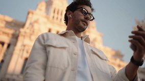 Male influencer records travel video for social media. Tourist man blogger holds up smartphone, framing himself against backdrop of historic architectural masterpiece in soft light of sunset