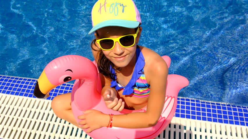 a child swims in a circle of flamingos in the pool. Selective focus.