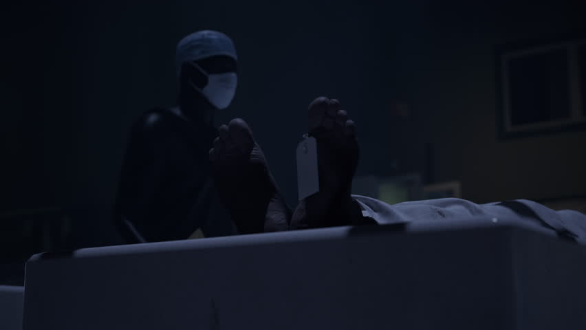 Two doctors standing in fron of a corpse in the morgue and ready to execute an autopsy