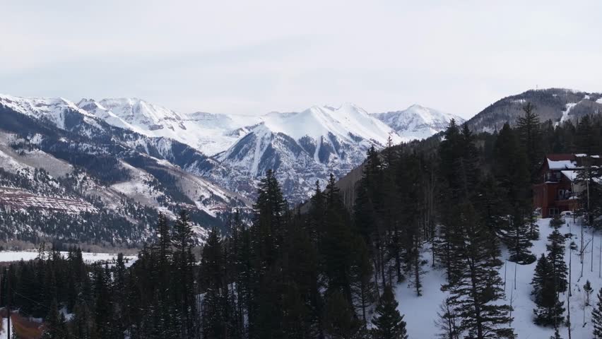 Winter landscape of Colorado Rocky Mountains over huts on the hill, snow and forest. Drone