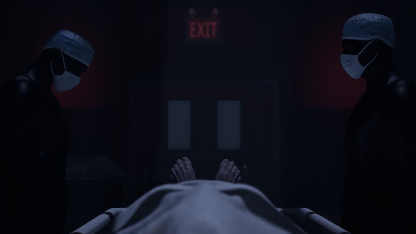 Two doctors standing in fron of a corpse in the morgue and ready to execute an autopsy