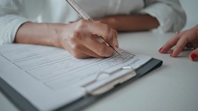 Closeup hands writing application papers on desk. Patient signing insurance form filling personal information at reception. Unknown african american visiting doctor in clinic. Medical system concept. - Powered by Shutterstock - Get 15% off with code: PIKWIZARD15