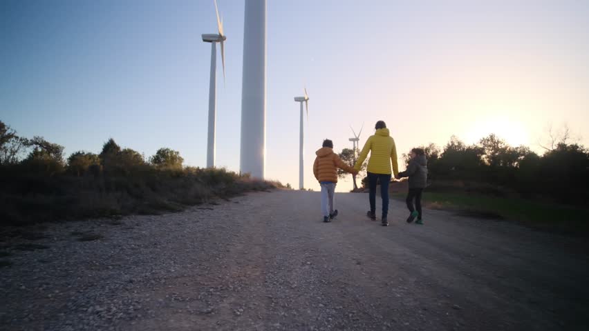 A heartwarming portrayal of a single mother guiding her two sons towards a sustainable future. Exploring green technology, wind turbines, and environmental conservation. Royalty-Free Stock Footage #3444729491