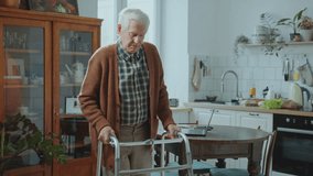 Elderly man using a walking frame to get around the house without assistance during the day. Tilt-down shot - Powered by Shutterstock - Get 15% off with code: PIKWIZARD15