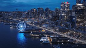 Aerial panorama of seafront and financial district skyscrapers and buildings, downtown Seattle at dark winter night light. 4K b roll drone shot of cityscape night scene. Illuminated night city USA