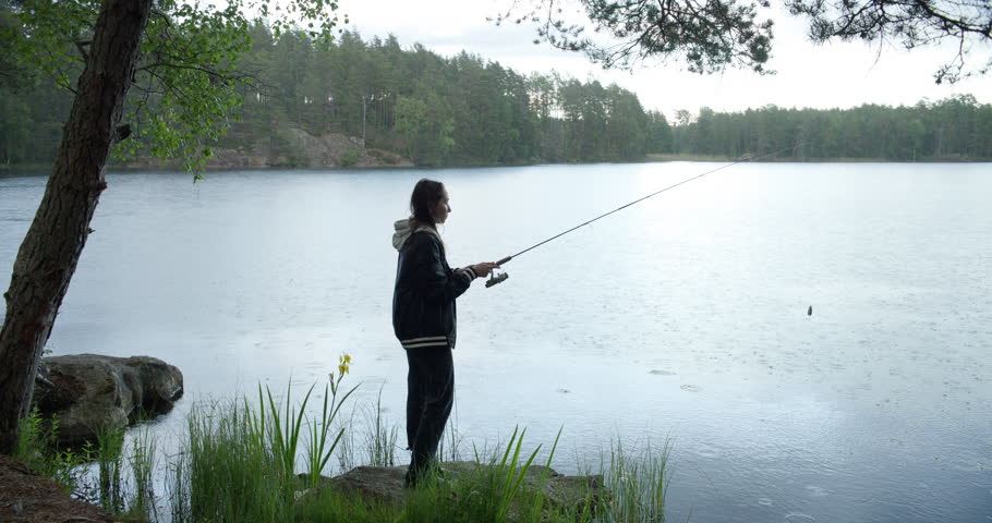 Teenage girl fishing in lake on rainy day Royalty-Free Stock Footage #3444866051
