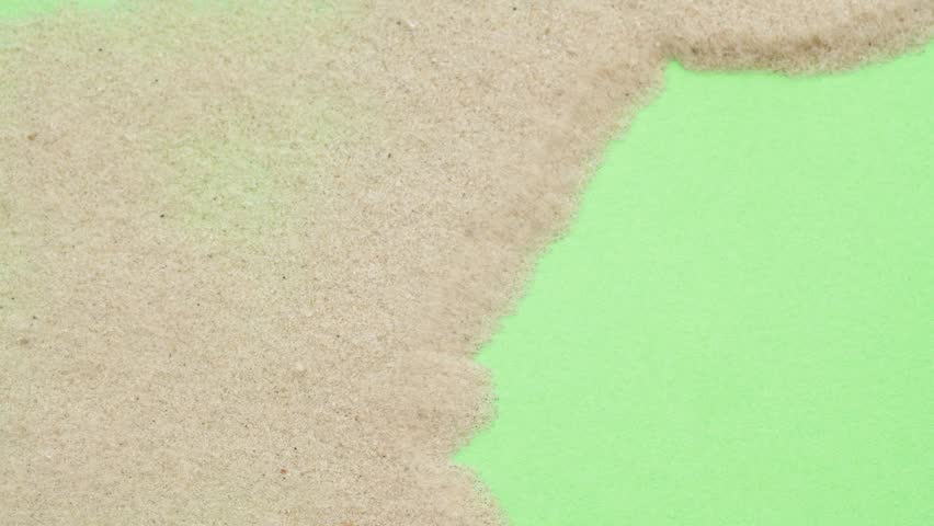 Closeup abstract sand transition blowing over green screen chroma key background