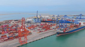 A drone flies over a vibrant array of shipping containers, showing the organized chaos of goods transit at a sea port with cranes. The sky is overcast, reflecting a bustling industrial atmosphere - Powered by Shutterstock - Get 15% off with code: PIKWIZARD15