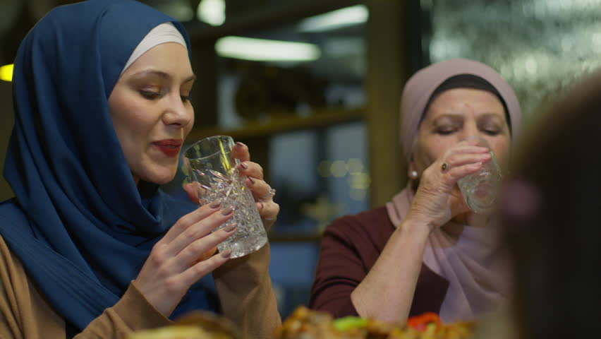 Elderly Mother and Young Daughter in Hijab Breaking Islamic Fast by Drinking Water at the Ramadan Evening Meal or Just Drinking Water at Eid Lunch