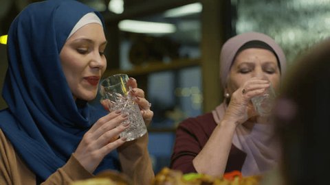 Elderly Mother and Young Daughter in Hijab Breaking Islamic Fast by Drinking Water at the Ramadan Evening Meal or Just Drinking Water at Eid Lunch Arkivvideo