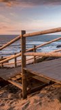 wooden steps leading down to a beautiful wild and deserted beach on portugal atlantic coast in vertical