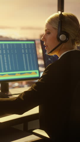 Vertical Portrait of Female Air Traffic Controller Talk on a Call in Airport Tower. Office Room is Full of Desktop Computer Displays with Navigation Screens, Airplane Flight Radar Data for the Team.