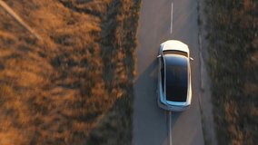 Aerial shot of electrical car driving through country road at summer evening. Modern vehicle passing rural highway. Ecology friendly car riding on electric charge along motorway. Top view. - Powered by Shutterstock - Get 15% off with code: PIKWIZARD15