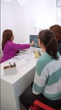 Female dentist in her office showing an oral x-ray on the computer screen to some patients. Vertical video