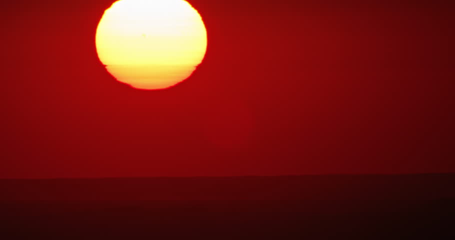 Timelapse of red sunset in desert, sun slowly sinks below horizon. Concept of end of the day, big hot circle down, epic dramatic view. Night will come soon