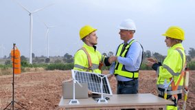 Engineer team standing shake hands in the meeting planing project install solar panel in the wind turbines farm. renewable energy installation project for the future world concept.4k video