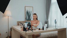 Young woman start live streaming beauty and cosmetic tutorial video content for social media. Beauty blogger smiles to camera while showing how to beauty care to audience or followers. Adit